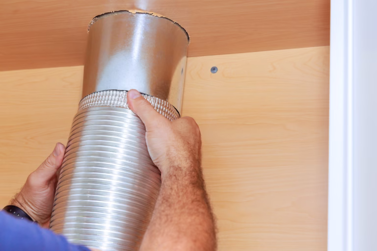 Installation worker placing tube for kitchen hood on a cabinet of kitchen