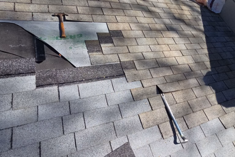 Roofing hammer and pry bar laying on asphalt shingles during a chimney flashing and roof termination repair in Gainesville, FL.