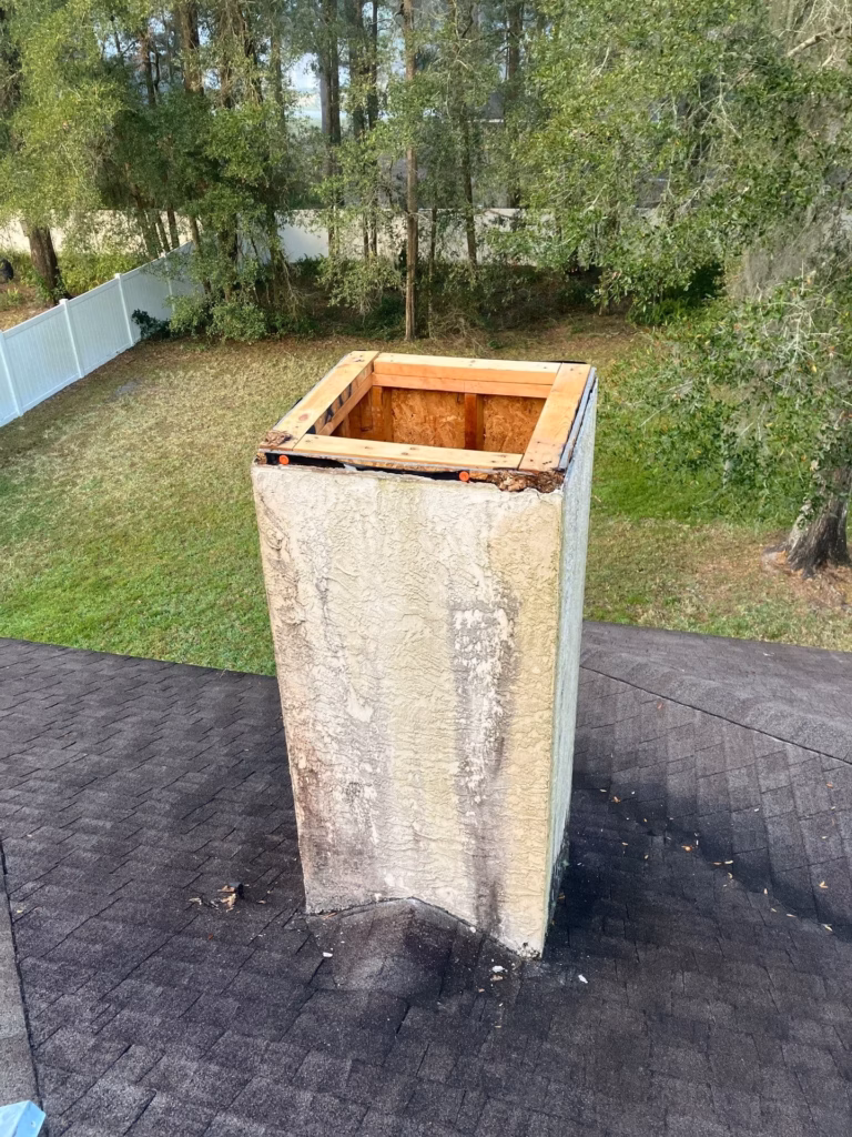 Open top of a weathered stucco chimney chase showing internal wood framing before custom chase cover installation in Ocala, FL.