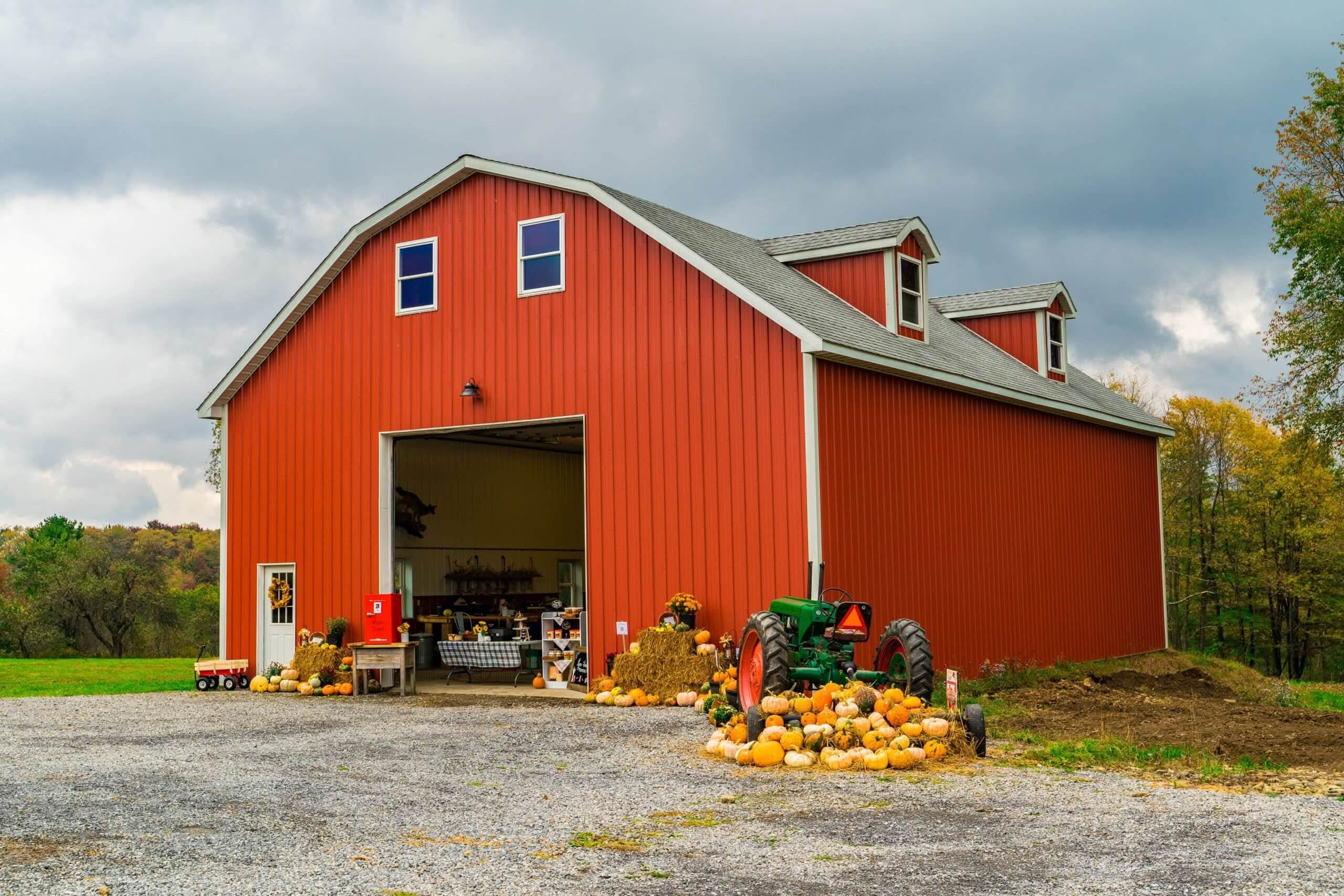 Red metal gambrel barn with an open bay door representing Always Home Repair farm and ag buildings
